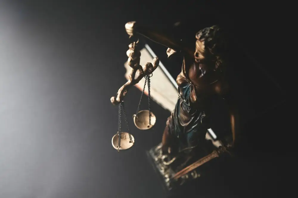 Statue of justice with scales on dark background, illustrating law and lived experience